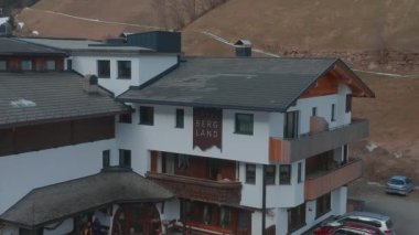 Bulutlu bir kış gününde, İtalya 'nın Tyrol kentinde, köyün ortasında çiçeklerle süslenmiş tipik ahşap bir dağ evi. Hava görünümü.