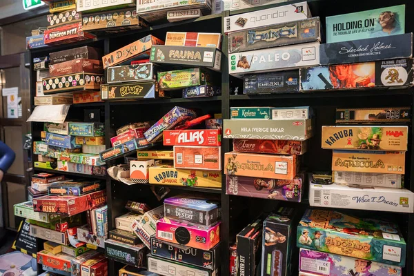 ゲームカフェの棚にいくつかのタイプのカラフルなボードゲームボックスは 顧客が再生または購入するには プレイヤーの数は毎日新しいオープンの速度と同じ成長 — ストック写真