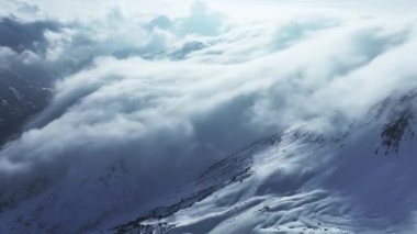 Tepeleri kar ve bulutlarla kaplı dağlık bir arazi. Ünlü St. Anton am Arlberg kayak merkezindeki dağların zirvelerini kaplayan sihirli bulutlar.