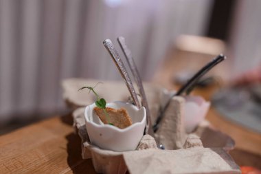 Lüks oteldeki lüks bir restoranın ahşap masasında yumurta kartonunda yumurta kabuğuyla bezenmiş otlar.