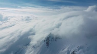 Tepeleri kar ve bulutlarla kaplı dağlık bir arazi. Ünlü St. Anton am Arlberg kayak merkezindeki dağların zirvelerini kaplayan sihirli bulutlar.