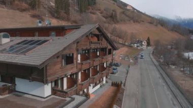 Bulutlu bir kış gününde, İtalya 'nın Tyrol kentinde, köyün ortasında çiçeklerle süslenmiş tipik ahşap bir dağ evi. Hava görünümü.