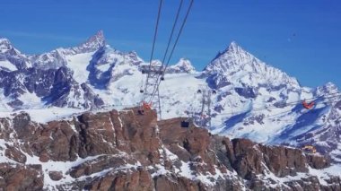 Zirve manzaralı kayak koltuğu kaldırma ve yamaçlar. Mavi gökyüzü ve parlak güneşle kar üstüne güzel bir kayak merkezi. Kayak kulübeleri, kayakçılar ve snowboardcular.. 