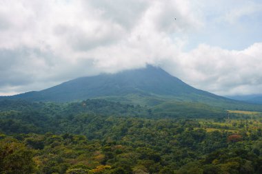 Bulutlu volkanik arka planıyla Kosta Rika 'nın muhteşem manzarası. Volkan Arenal 'in panoraması, La Fortuna, Kosta Rika' daki muhteşem pitoresk gölü yansıttı. Orta Amerika.