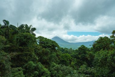 Bulutlu volkanik arka planıyla Kosta Rika 'nın muhteşem manzarası. Volkan Arenal 'in panoraması, La Fortuna, Kosta Rika' daki muhteşem pitoresk gölü yansıttı. Orta Amerika.