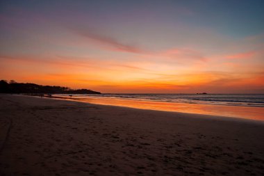 Kosta Rika 'da gün batımında bulutlu gökyüzü altında güneş ışığının yansımasıyla kumlu sahil manzarası, doğa ve seyahat konsepti..