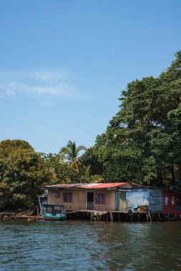 Güneşli bir günde, güneşli bir günde, köyün güzel, eski, eski nehir kıyısında bir ev tropikal yaz ikliminde yeşil ağaçlarla çevrili bir liman kenti.