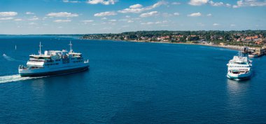 Ferry boat floating open sea, transportation liner shipping cars and people from Denmark Helsingor to Sweden Helsinborg. Dramatic sky in background, day scene.