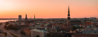 Riga, Letonya 'da yaz günbatımı. Gün batımında Letonya 'nın başkenti Riga' nın hava manzarası. Şehirden geçen güzel binalar, köprüler ve nakliye araçları.