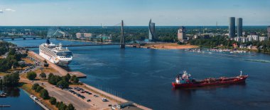 Riga, Letonya 'da yaz günbatımı. Gün batımında Letonya 'nın başkenti Riga' nın hava manzarası. Şehirden geçen güzel binalar, köprüler ve nakliye araçları.