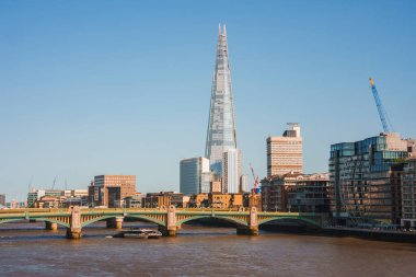 Arka planda açık gökyüzü olan binaların arasında çömlek kulesi. Londra 'nın şehir merkezi. Güneşli bir günde Thames nehri üzerindeki Southwark Köprüsü.