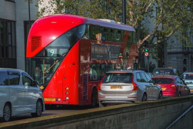 Kırmızı otobüs yolda arabalarla hareket ediyor. Şehrin caddesindeki araçlar. Londra 'da güneşli bir gün..