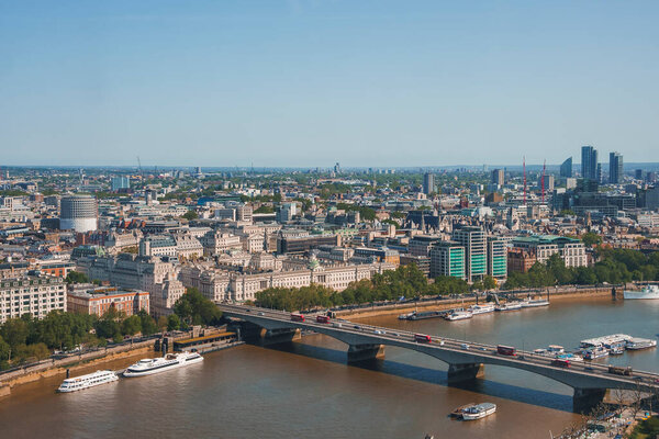 Aerial shot of vehicles moving on waterloo bridge. Beautiful view of river Thames during sunny day. Cityscape under clear blue sky.