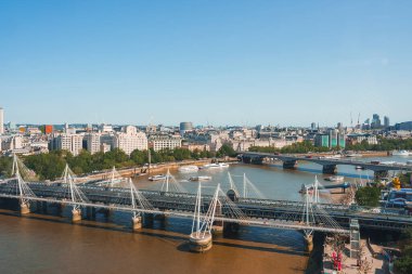 Hungerford Köprüsü ve Golden Jubilee Köprüsü 'nün hava görüntüleri. Güneşli bir günde güzel Thames nehri. Açık mavi gökyüzü altında şehirli binalar.