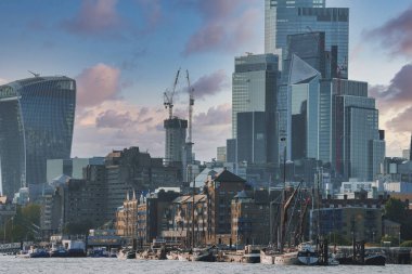 Thames nehrinin limanına demirlemiş yelkenli mavnası. Arka planında bulutlu gökyüzü olan modern gökdelenler. Güneşli bir günde başkent Londra 'nın manzarası.