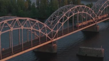Riga, Letonya 'da yaz günbatımı. Gün batımında Letonya 'nın başkenti Riga' nın hava manzarası. Şehirden geçen güzel binalar, köprüler ve nakliye araçları.