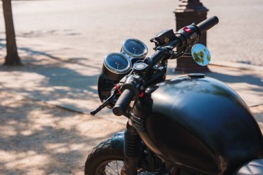 Siyah Triumph motosikleti güneşli gökyüzünün altında, bej rengi Zafer Takı 'nın önüne park etmiş..
