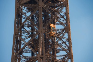 Fransa, Paris 'teki Eyfel Kulesi' nin açık mavi gökyüzü ve yeşil manzarasıyla yakın görüntüsü.