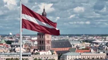 Letonya 'nın güzel bayrağı rüzgarda dalgalanıyor Riga' nın eski kasabası Letonya 'nın arka planında. Vatansever video. Riga hava görüntüsü.