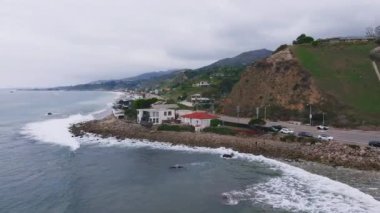 California 'daki Malibu sahilinin 4K hava aracı görüntüsü. Mavi Pasifik Okyanusu, dalgalar geliyor ve arka planda güzel evler var..