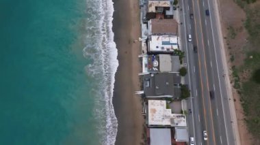 California 'daki Malibu sahilinin 4K hava aracı görüntüsü. Mavi Pasifik Okyanusu, dalgalar geliyor ve arka planda güzel evler var..
