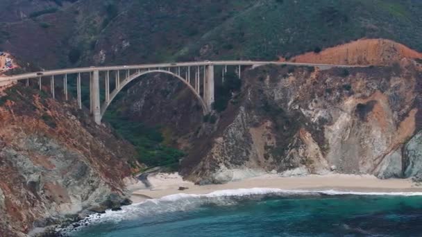 太平洋は モントレーの南ではなく カリフォルニアの美しい海岸に洗い流されます カリフォルニア州ビッグサー海岸のビクスビー クリーク橋の空中撮影 — ストック動画