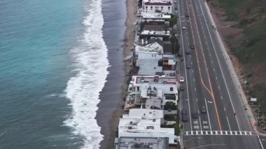 California 'daki Malibu sahilinin 4K hava aracı görüntüsü. Mavi Pasifik Okyanusu, dalgalar geliyor ve arka planda güzel evler var..
