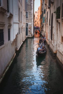 Venedik 'te dar bir kanalda gezinen bir gondolun manzarası şehrin ikonik su taşımacılığını gösteriyor. Bu fotoğraf, tarihi İtalyan şehrinin ebedi cazibesini yansıtıyor..