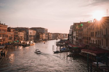 Venedik 'teki ikonik Büyük Kanal' ın üzerinde güzel bir günbatımı berrak gökyüzü ve suda canlı bir yansıması var. Arka plandaki binaların silueti huzurlu ve resimsel bir sahne yaratır.