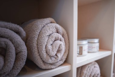 Şatafatlı ve zarif banyo havluları, çeşitli boyutlarda ve şekillerde bir rafa yerleştirilmiş. Genel atmosfer rahatlatıcı ve rahatlatıcı, spa benzeri bir deneyim için mükemmel..