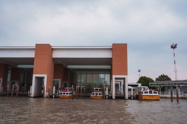 Bulutlu bir günde, etrafı bulanık ve sular altında kalmış büyük, dikdörtgen bir binanın havadan görünüşü. Tekne ve enkaz olmadan kasvetli ve kasvetli bir ruh hali.