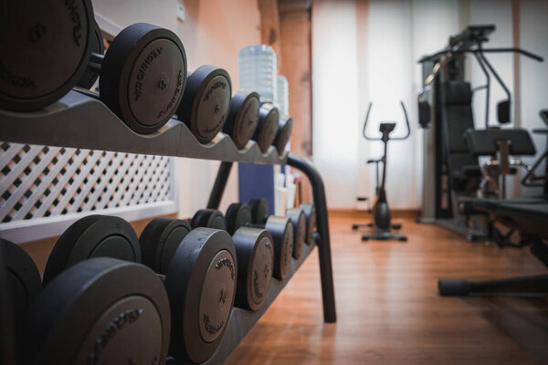 Modern gym room with a variety of dumbbells and exercise equipment. Perfect for strength training and fitness workouts.