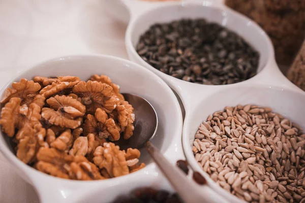 A variety of nuts and seeds, including walnuts, pistachios, and sesame seeds, are displayed in a bowl on a table. Perfect for Venetian hotel and restaurant interior design inspiration.
