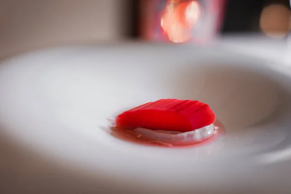 A close-up of a red object in a white bowl, with soft, diffused lighting creating a warm, romantic glow. Perfect for food and romance-themed concepts.