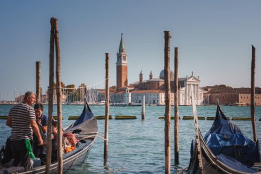 İtalya, Venedik 'te sakin sularda gondolların sakin bir sahnesi. Arka planda, kenetlenmiş gondollarla ve geleneksel Venedik mimarisiyle huzurlu bir ortam. Huzurlu ve huzurlu bir atmosfer..