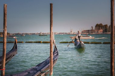 Venedik, İtalya 'da sakin sularda yüzen renkli gondollar, arka planda şehir. Huzurlu sahne güzel bir yaz gününün özünü yakalar. Venedik 'in ikonik cazibesini yansıtır..