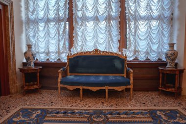 Süslü beyaz ve mavi perdeleri olan bir odada klasik ve zarif bir mavi kanepe. Venedik tarzı lüks iç mekanların sergilendiği Venedik fotoğraflarının bir parçası..