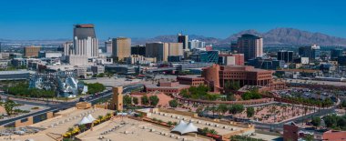 Modern yüksek binalar, eşsiz mimari, yeşil parklar ve dairesel bir kompleks ile Las Vegas 'ın havadan görünüşü, berrak mavi gökyüzü altında dağlık bir zemin üzerine kuruludur..