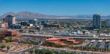 Las Vegas, ABD 'de yoğun bir park alanına sahip, berrak mavi gökyüzü altında dağlarla çevrili, modern yüksek binalara sahip bir havacılık şehri..