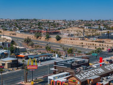 Barstow, California 'nın yükseltilmiş manzarası, hareketli şehir manzarası, ticari markalar ve 66. Otoyol trafiği, sakin tepeler ve açık gökyüzü zeminine göre ayarlanıyor..