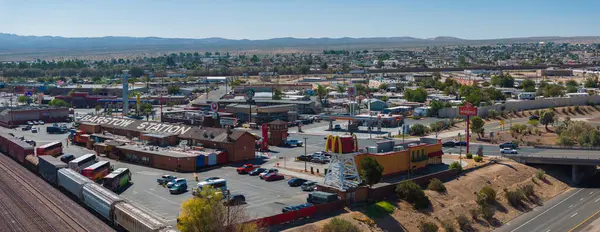 Barstow, California 'nın havadan görünüşü, çeşitli mimari, işlek yollar, yeşil alanlar ve yerel ticareti ve ulaşımı ön plana çıkaran dağlık bir ufuk..