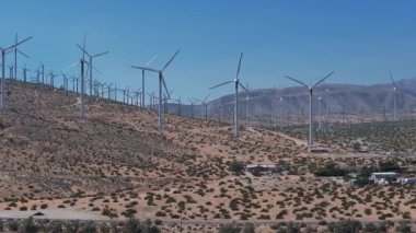 ABD 'nin Palm Springs kentindeki geniş ölçekli bir rüzgar türbini tarlasının havadan görünüşü, açık gökyüzünün altında altın-kahverengi çöl manzarası arasında durgun türbinler..