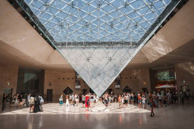 Büyük cam piramit Paris 'teki Louvre Müzesi' nin ana girişi olarak hizmet veriyor. Etrafı insanlar ve müze binalarıyla çevrili..