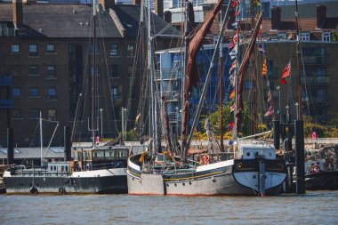 Thames nehir kıyısına demirlemiş tekneler. Arka plandaki apartman daireleri. Güneşli bir günde Londra 'da binalar.