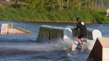 Genç adam parkta wakeboard yaparken profesyonel seviyede zor numaralar yapıyor. Aşırı su sporları. Yazın aksiyon zamanı. Wakeboardcu numaralar yapıyor.. 