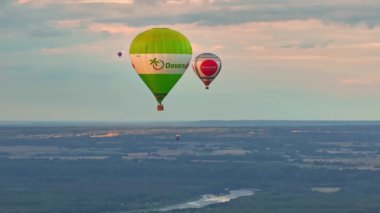 Sıcak hava balonları ormanın üzerinde ve göllerin üzerinde alacakaranlıkta uçuyor. Gün batımında hava balonunun hava görüntüsünü kapat..