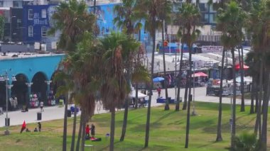 Los Angeles, ABD 'deki güzel Venedik plaj bölgesi. Venedik sahilinin havadan görünüşü, insanların sörf yapması, sahilde yürümesi ve farklı dükkanlara ve barlara girmesi..