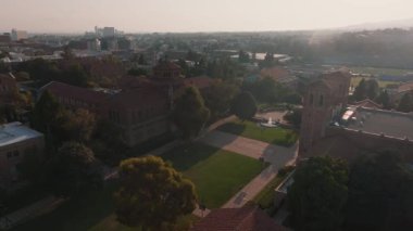 UCLA kampüsünün havadan görünüşü altın ışıkla yıkandı, Roma Uyanışı ve yemyeşil ortamda Gotik mimari sergilenirken, Royce Hall merkezde sergilendi..