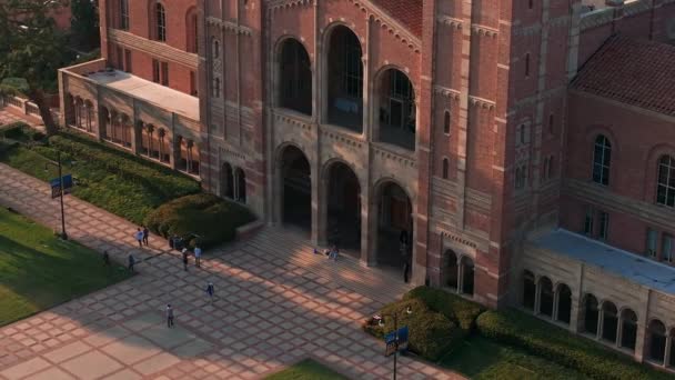 加州大学洛杉矶分校校园的空中景观闪烁着金光闪闪的光芒 展示了罗曼式复兴与哥特式建筑 绿树成荫 以罗伊斯大厅为中心 — 图库视频影像