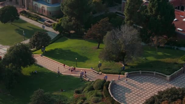 加州大学洛杉矶分校校园的空中景观闪烁着金光闪闪的光芒 展示了罗曼式复兴与哥特式建筑 绿树成荫 以罗伊斯大厅为中心 — 图库视频影像